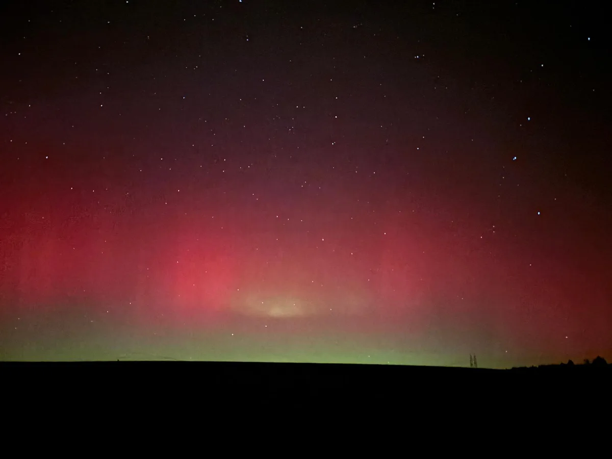 Man sieht grüne, violette und pinke Polarlichter am dunklen Nachthimmel.